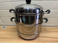 Photo of the 3 piece stainless steel steamer pot set stacked together with lid on top, showing the pot base, steamer insert, and lid.