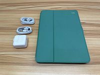Top-down photo of teal iPad case, two Lightning cables, and Apple charger on wood table