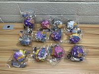 Photo showing 12 new 3D Bubble Pop Balls individually packaged, placed on a wooden surface against a wall.