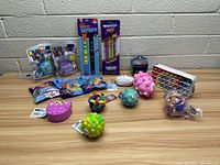 Image showing multiple new fidget toys including massage balls, pop-it toy, glow sticks, silicone strings, character toys, and abacus bead toy.