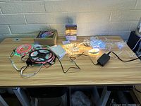 Photo showing multiple LED strips and string lights laid out on a wooden table, with power adapter and remote included.