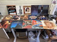 Wide shot showing 15 vinyl records on table featuring country and southern rock artists