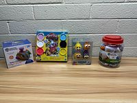 Photo of the lot showing the Learning Resources airplane toy, Play-Doh set, finger puppets, and counting counters jar placed against a wall.