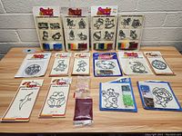 Top-down image showing entire lot of vintage Make It and Bake It sets laid out on a wooden surface with clear details of molds and colored sand packages included