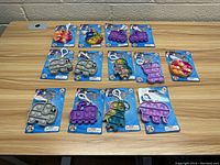 13 Push Pop Squishems new keychains and backpack clips in original packaging, varying shapes and colors arranged on table.