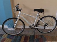 Full side view of white Trek Alpha bicycle with flat handlebars and black saddle indoors on tile floor.