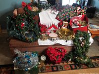 Wide view of the entire Christmas lot showing wreaths, centerpiece, garlands, and various decorative items arranged on a couch and floor.