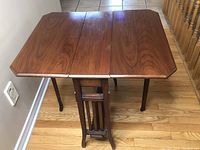 Front view of vintage wooden gate leg occasional table with open leaves and visible grain.