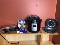 Wide shot showing all items in the lot on display, including Instant Pot, pans, measuring spoons, clips, and cookbooks.
