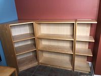 Full view of the three maple shelving units arranged side by side, showing the corner unit on the left and two straight shelves to the right.
