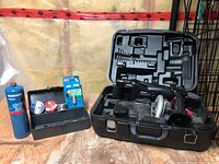 Coleman Powermate saws in metal case, with some accessory tools inside the case and shown with carrying lock latches open.