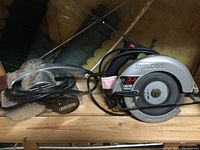 Craftsman bell sander placed next to Skilsaw circular saw on wooden shelf, showing overall condition and size comparison.