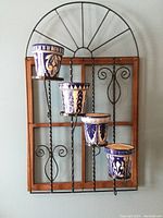 Full front view of the wooden and metal wall-mounted plant stand holding four blue and white ceramic pots arranged in staggered heights.