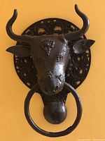 Front view of the metal steer head sculpture showing embossed details and iron ring.