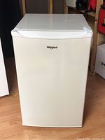Front view of white Whirlpool mini fridge showing smooth door with logo.