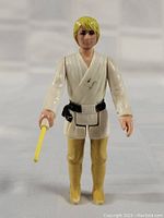 Front view of the Luke Skywalker action figure holding a yellow lightsaber, showing some wear and paint marks on the tunic.