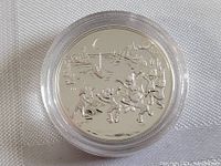 Another reverse side image emphasizing reflective nature and detail of the silver coin, with design of children playing at night near water under moonlight.