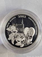 Close-up front view of 2002 Nova Scotia silver half dollar coin in protective capsule.