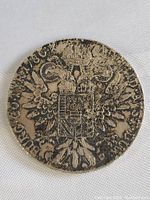 Full face of the antique silver Thaler coin showing the double-headed eagle and coat of arms design