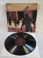 Original Dawn of the Dead soundtrack vinyl record with black disc and album cover showing zombies in a mall scene.