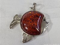 Front view of the fish pendant showing amber stone body and silver metal fins.