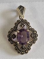 Front view of the sterling silver amethyst pendant showing purple faceted center stone and marcasite decoration.