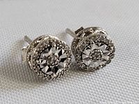 Close-up view of the pair of vintage sterling silver earrings with textured starburst central design and granulated silver detail set on post backs.