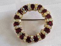 Top-down view of vintage round brooch pin with red and clear stones.