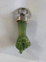 Front view of the green jade fist pendant with silver bail and loop.