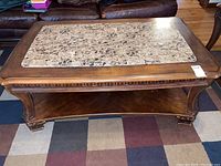 Top view of wooden coffee table showing stone insert with chips and wood surface wear