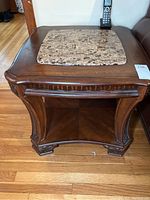 Front view of wooden end table with carved legs and stone insert top.