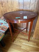 Side view of wooden oval end table showing four legs and cross braces