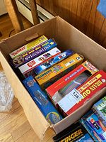 Box showing multiple board games including Twister, Smithsonian, Brain Quest, Beat The Parents, Numbers, Clue Junior, and others.