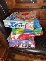 Stack of 5 boxed games including Yeti in My Spaghetti, Ladybug Game, Dino Dissection, Uncle Wiggly, and Battleship.