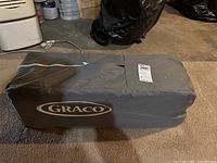 Gray carrying case with Graco logo. Zippered soft fabric case for storing and carrying playpen.
