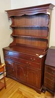 Full view of the wooden hutch cabinet with three shelves on top and storage below.