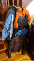 Photo showcasing five Columbia jackets on stairs, featuring gray/blue, orange/black, dark brown, and two additional jackets in blue and gray shades.