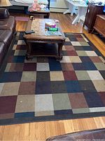 Full view of rectangular area rug under coffee table showing multicolor geometric square pattern