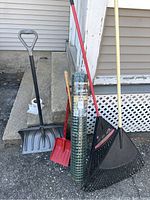 Photo showing all yard tools and fencing included in the lot, arranged upright against house exterior.