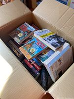 Box filled with various young adult books including multiple Great Illustrated Classics titles and other books such as 'Treasure Island'.