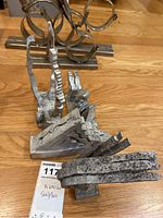 Photo showing four abstract sculptures made of aluminum and stainless steel placed on a wooden floor.