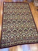 Full view of the rectangular area rug on wooden floor showing floral pattern and border.