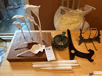 Overview of calla lilies sculpture on wooden base with decorative bowl, spoon, picture holders and taper candles.
