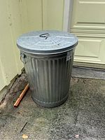 Full view of galvanized metal trash can with lid outside