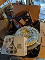 Cardboard box containing Romex and underground cable, overhead and flood light fixtures with commercial service floodlight bulb box and track lighting fixture box on top