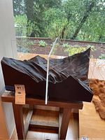 Side view showing textured dark terrain base with vertical glass panel mounted in the center.