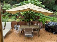 Full view of set with table, open umbrella, four sling chairs and two chaise lounges on deck