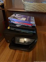 Photo shows HP OfficeJet Pro 6978 printer with several paper packs on top including Apollo and Masterpiece brands.