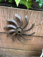 Close-up image of cast iron harrow sculpture showing curved blades and central square hole.