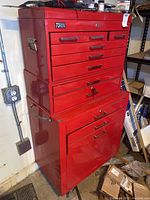 Front view of red Torin metal tool box showing top and bottom sections with drawers, placed in workshop space.